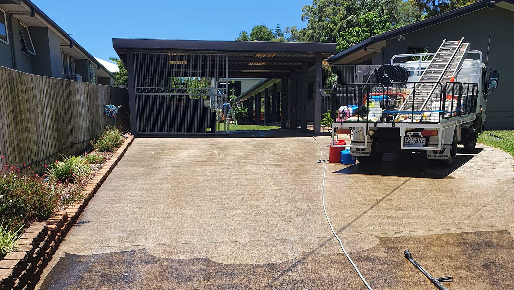 Residential driveway in North brisbane home half pressure cleaned with truck in background