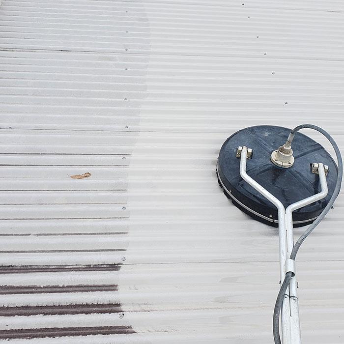 Pressure cleaning machine on aluminium roof half cleaned